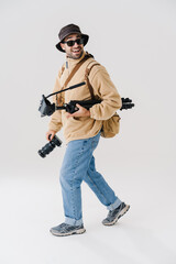 Excited young photographer walking with digital camera and tripod