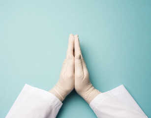 two male hands in white latex gloves, doctor's palms on a blue background in a prayer position