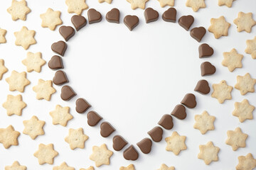 pralines of chocolate are laid out in the shape of a heart, outside lie the cookies in the shape of a star