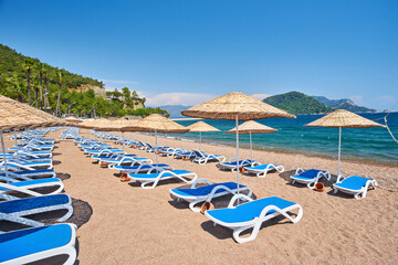 beach on the sea in cloudless weather. Sunset on a sandy beach with umbrellas and sun loungers