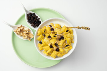cornflakes, raisins, nuts and muesli in a green plate on a table