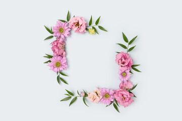 Empty flower frame made of pink eustoma on blue background. Greeting card template with copyspace. Spring concept.