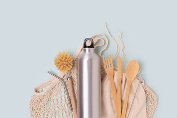 Wooden cutlery, metallic bottle, textile bags on a blue background. Zero waste concept with copyspace.