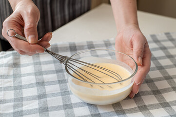 The process of preparing the dough. The woman whips the egg mixture with a whisk. Ingredients for...