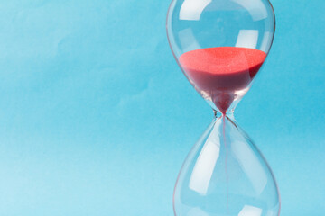 Crystal hourglass on blue background as a concept of passing time for business term, urgency and...