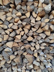 Woodpile. Wall firewood. Background from dry chopped logs in a heap. A wall of firewood, a background of dry chopped firewood. Alternative fuel concept. A snapshot of the natural background.