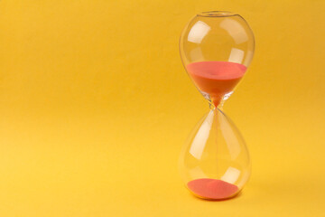 Crystal hourglass on yellow background as a concept of passing time for business term, urgency and...