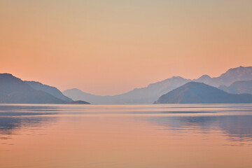Fototapeta na wymiar Mountain reflected sunrise in calm sea