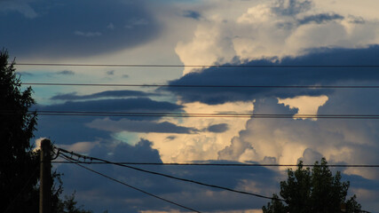 Cumulonimbus observés au loin, derrière une ligne électrique
