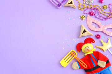 Purim celebration concept (jewish carnival holiday) over wooden purple background. Top view, flat lay