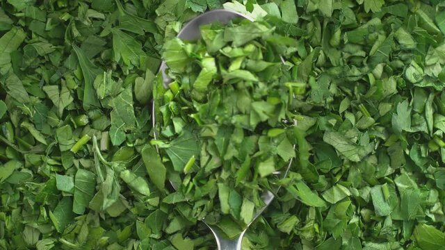 Chopped Parsley on Silver Tablespoon in Macro Falling onto Green Herbs in Slow Motion