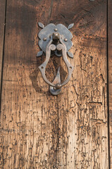 Old medieval metal door knocker on wood worm eaten door close