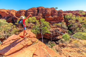 Panoramic view of woman at Kings Canyon Rim Walk with footbridge over Garden of Eden, Watarrka...