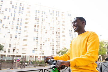 happy young black man with scooter in city