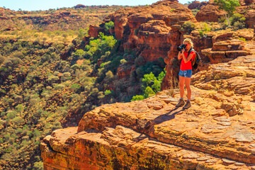 Travel photographer taking pictures of sandstone cliff in Kings Canyon Watarrka National Park....