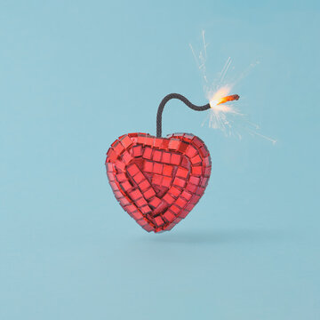Red heart-shaped fuse bomb against pastel blue background. Valentines day party concept.