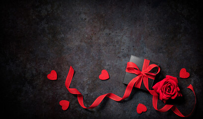 Valentines day red roses and gift box arranged on a dark background