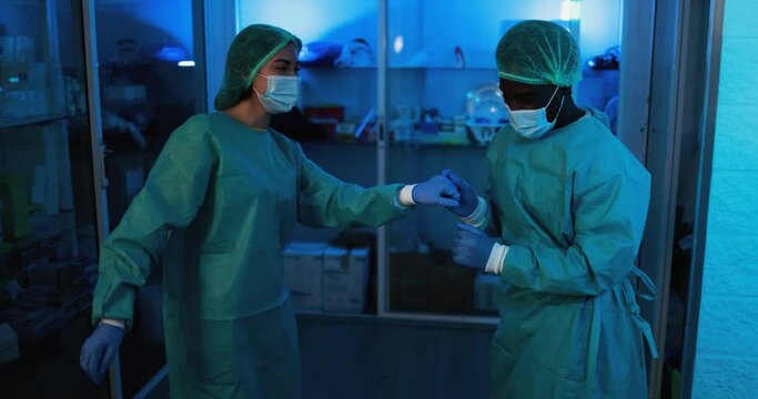 Doctor and nurse dancing in hospital during coronavirus pandemic outbreak - Multiracial medical workers having fun inside clinic