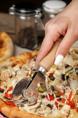 woman's hand cuts the pizza with a pizza knife. Home made pizza. Home delivery. 