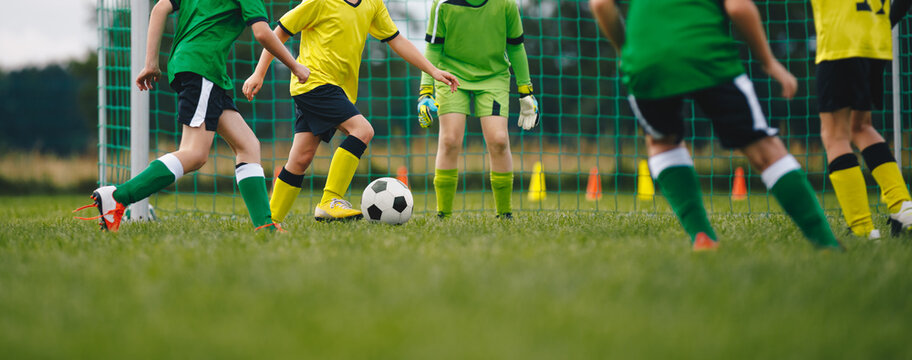 Horizontal image of kids playing football. Happy boys kicking classic soccer ball on grass field. School children compete in sports game on training pitch