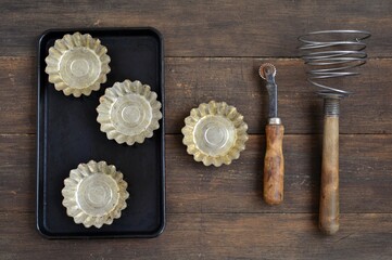 Vintage kitchen baking tools with cupcake molds on a baking sheet on a worn wooden background...