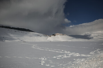 Panoramic view of Castelluccio di Norcia little mountain town covered by snow in winter season, Umbria, Italy