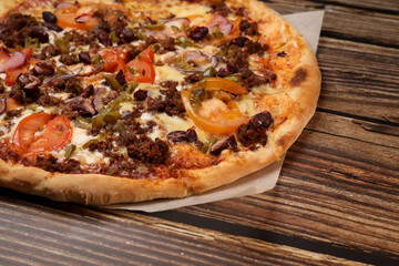 Top view of fresh baked pizza with meat and vegetables on a wooden table. Pizza delivery. Take away. 