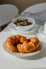 Appetizing bagel (croissant) on a white table with a served breakfast.