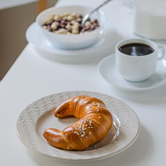 Appetizing bagel (croissant) on a white table with a served breakfast.