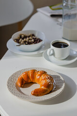 Appetizing bagel (croissant) on a white table with a served breakfast.