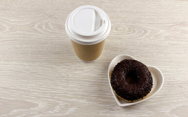 Wooden background with chocolate donut and glass with coffee