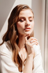 beautiful woman in white robe at the window.morning of bride before wedding