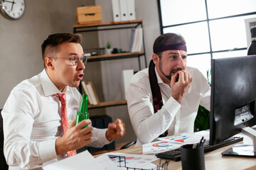 Two friends drinking beer in office. Colleagues are celebrating a big accomplishment at work..