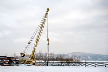Fototapeta premium Construction crane on a winter day on a frozen river