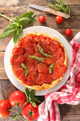 tomato quiche and herbs on wood background