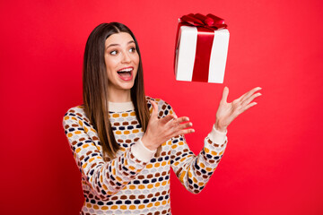 Portrait of impressed girl catch present wear colorful sweater isolated on red color background