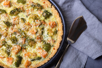 Quiche (open pie) with trout, broccoli and cheese. Homemade unsweetened pastries, traditional pie. Close-up.