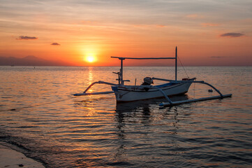 Naklejka premium Atardecer en la playa en Bali con barcos fondeados en la arena. Lovina. 