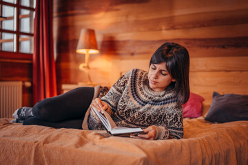 Obraz premium Beautiful female at home in winter time reading a book