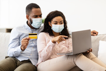 Black couple in medical mask using laptop and credit card
