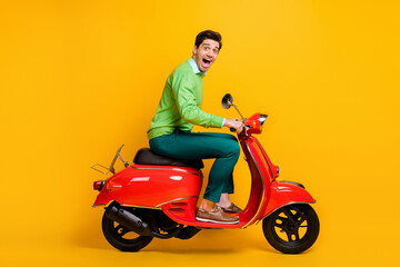 Fototapeta na wymiar Full length profile photo of handsome guy driving moped open mouth wear sweater isolated on yellow color background