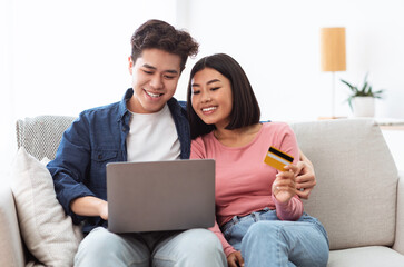 Fototapeta premium Japanese Couple Shopping Online Using Laptop And Credit Card Indoor