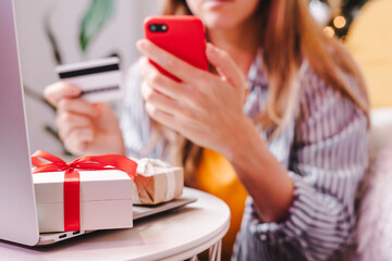 Close up of woman hands with mobile cellphone, credit card, gifts and laptop. Online shopping at...