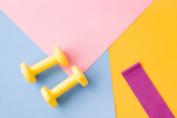 Yellow dumbbell color on pink, blue and yellow mat. Design of a sports poster or banner in fashionable colors of 2021