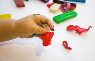 child molded a heart from plasticine, holds in his hands, top view, creativity for children, classes at home