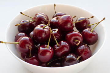 Naklejka na ściany i meble Juicy sweet cherries in a glass bowl isolated on white