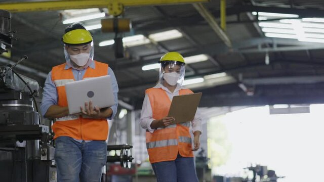 Asian machine engineer put on mask and face shield while working in an industrial plant. Safety in the work to prevent COVID-19 and Dust PM2.5. Work as team based on technology to check equipment.