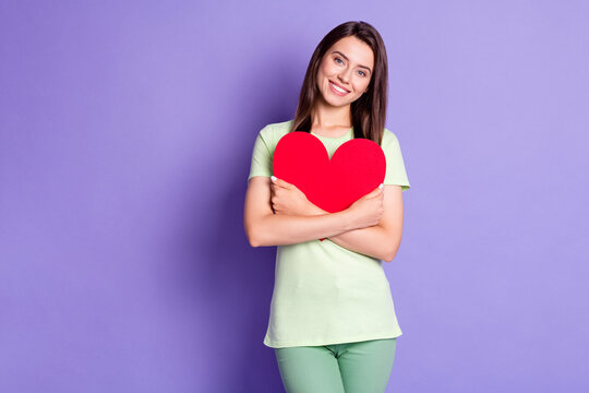 Photo portrait of cheerful girl wearing green t-shirt hugging embracing heart on valentines day isolated on vibrant purple color background