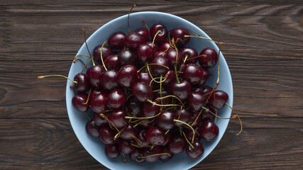 Ripe cherry in a blue plate top view, closeup, top view