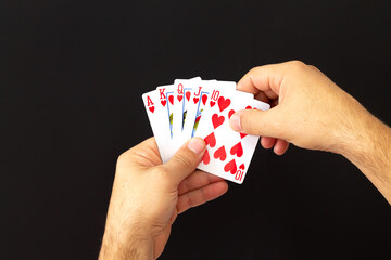 Male hands holding combination of royal flush poker cards on dark background